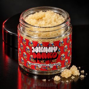 Johnny Danko gas extract sealed jar with red branded label and golden sugar crystals inside, positioned on dark surface